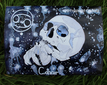 Load image into Gallery viewer, A print copy on the grass of a Cancer star sign watercolour painting with a black and grey background and white skull with a crab.
