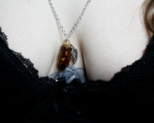 Load image into Gallery viewer, A close up of a woman wearing a silver necklace with a leaf and small corked bottle of red jasper crystals.
